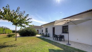 Une maison avec un patio, une table et des chaises, et un grand parasol.