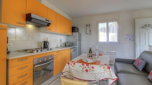 Een praktische keuken met een gasfornuis, oven en een eethoek met een tafel gedekt voor twee personen.