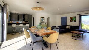 Un espai de vida modern amb zona de dinar, cuina i una finestra gran que ofereix una vista.