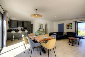 A modern living space with a dining area, kitchen, and a large window providing a view. - Villa Tre Funtane - MONTICELLO (MONTICELLO)