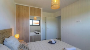 Une chambre à coucher avec un lit, une table de chevet, une lampe et une armoire avec un miroir.