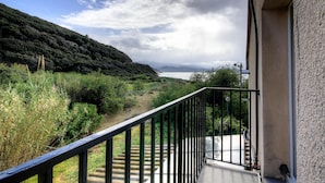 En balkon med udsigt over et kystlandskab, en trappe og en bygning med en detaljeret facade.