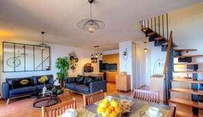 Ein modernes Wohnzimmer mit Sofa, Esstisch und Wendeltreppe.
