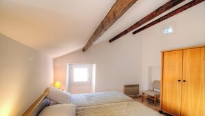 A bedroom with a bed, a chair, a wardrobe, a window, and a radiator. - A Torra - AITI - Gîte (AITI)