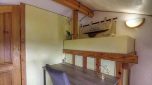 Ein Stockbett mit Holz Kopfteil, ein kleiner Tisch mit Stuhl und eine Wandleuchte.