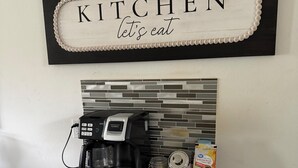 A kitchen counter with a coffee maker, a box of coffee, and a trash can. -  Spacious 4-bedroom Houston Retreat Near NASA, Downtown & Galveston Cruises (Houston)