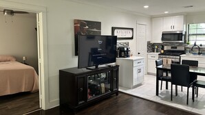 A modern kitchen with white cabinets, a black countertop, and a dining area with a table and chairs. -  Spacious 4-bedroom Houston Retreat Near NASA, Downtown & Galveston Cruises (Houston)