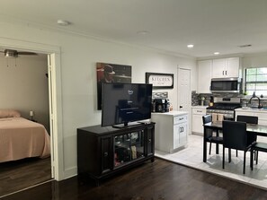 A modern kitchen with white cabinets, a black countertop, and a dining area with a table and chairs. -  Spacious 4-bedroom Houston Retreat Near NASA, Downtown & Galveston Cruises (Houston)