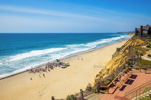 A beach with a boardwalk, a lifeguard tower, and a building with cylindrical towers. - Oceanfront Solana Beach 2 BDR Condo (Solana Beach)
