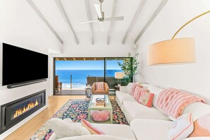 A modern living room with a fireplace, a flat-screen TV, a sofa, and a view of the ocean. - Oceanfront Solana Beach 2 BDR Condo (Solana Beach)