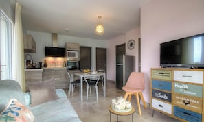 A modern living room with a sofa, a dining table with chairs, a television, a kitchen area with appliances, and a cabinet with drawers. - Chez Dumè 2B59 - CASTELLARE DI CASINCA (CASTELLARE DI CASINCA)