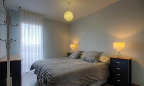 A bedroom with a bed, two bedside tables with lamps, a coat rack, and a window with sheer curtains. - Chez Dumè 2B59 - CASTELLARE DI CASINCA (CASTELLARE DI CASINCA)