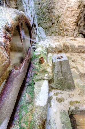 Eine Steinstruktur mit einem Wasserspiel, möglicherweise einer Fontäne, und einem Loch im Stein.