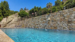 Ein Schwimmbecken mit einer Steinmauer und einem Metallzaun.