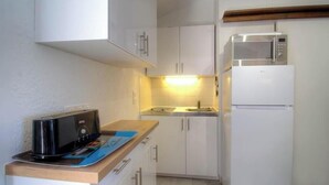 Eine kleine Küche mit weißen Schränken, einer Mikrowelle, einem Toaster und einem Spülbecken.