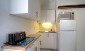 Eine kleine Küche mit weißen Schränken, einer Mikrowelle, einem Toaster und einem Spülbecken.