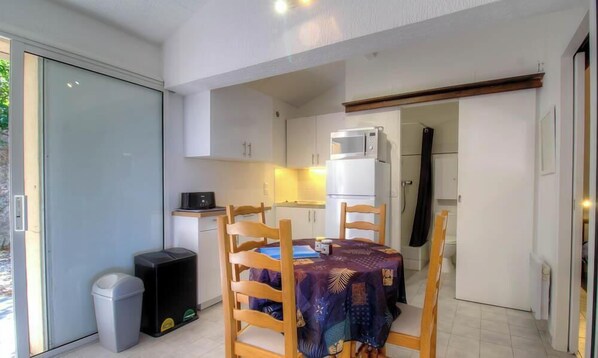 Eine kompakte Küche mit Mikrowelle, Kühlschrank und einem Essbereich mit Tisch und Stühlen.