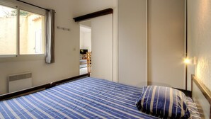 Ein Schlafzimmer mit Bett, Fenster, Spiegel und Tür.