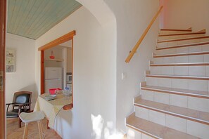 A staircase with wooden handrails, a dining area with a table and chairs, and a kitchen area with appliances. - Le Romarin - SOTTA - Gîte (SOTTA)