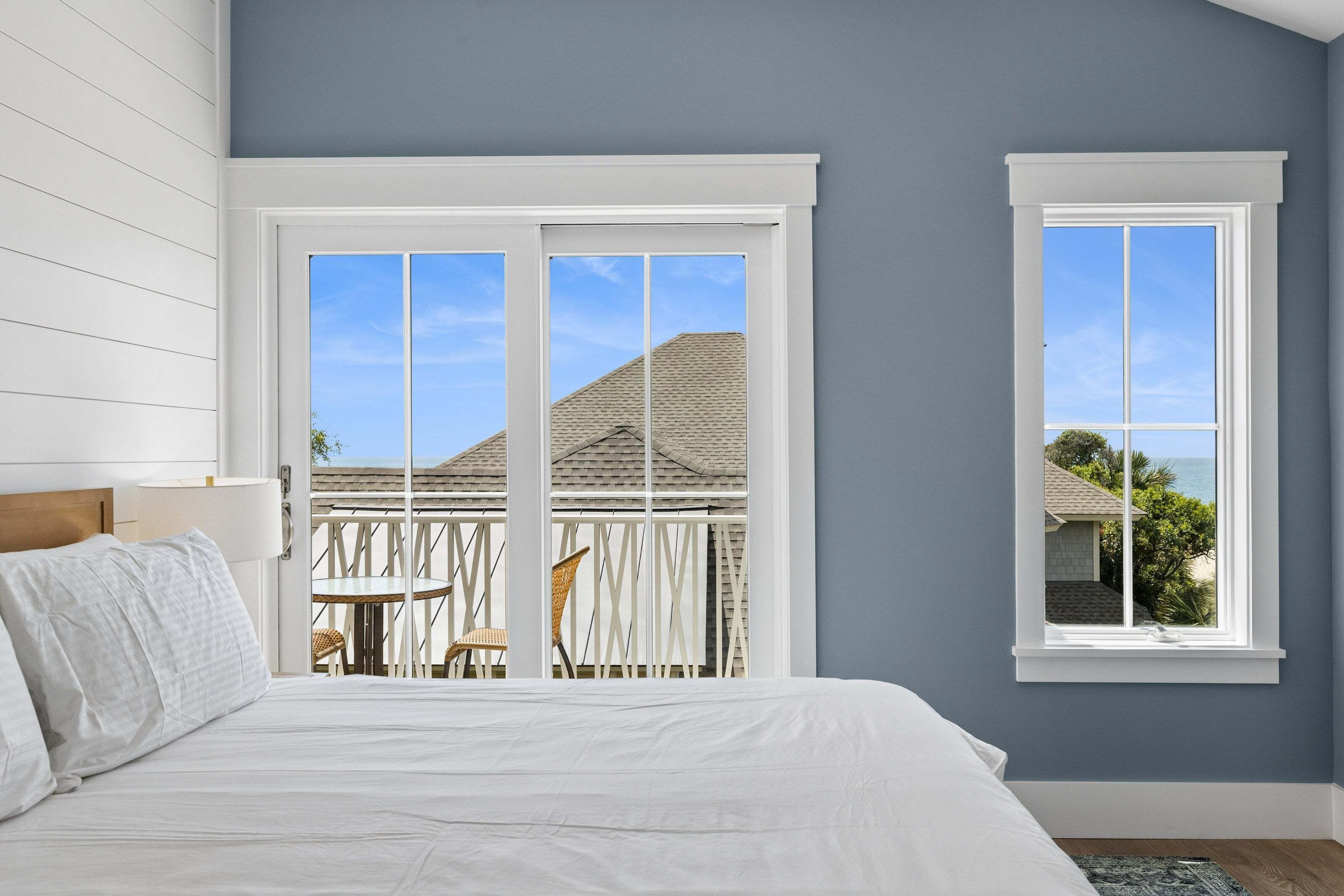 Ein Schlafzimmer mit Bett, Fenster und Balkon mit Stuhl und Tisch.