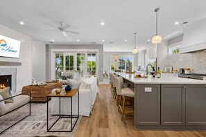 Una cocina moderna con una isla central, zona de comedor con sofá y mesa, y una chimenea.
