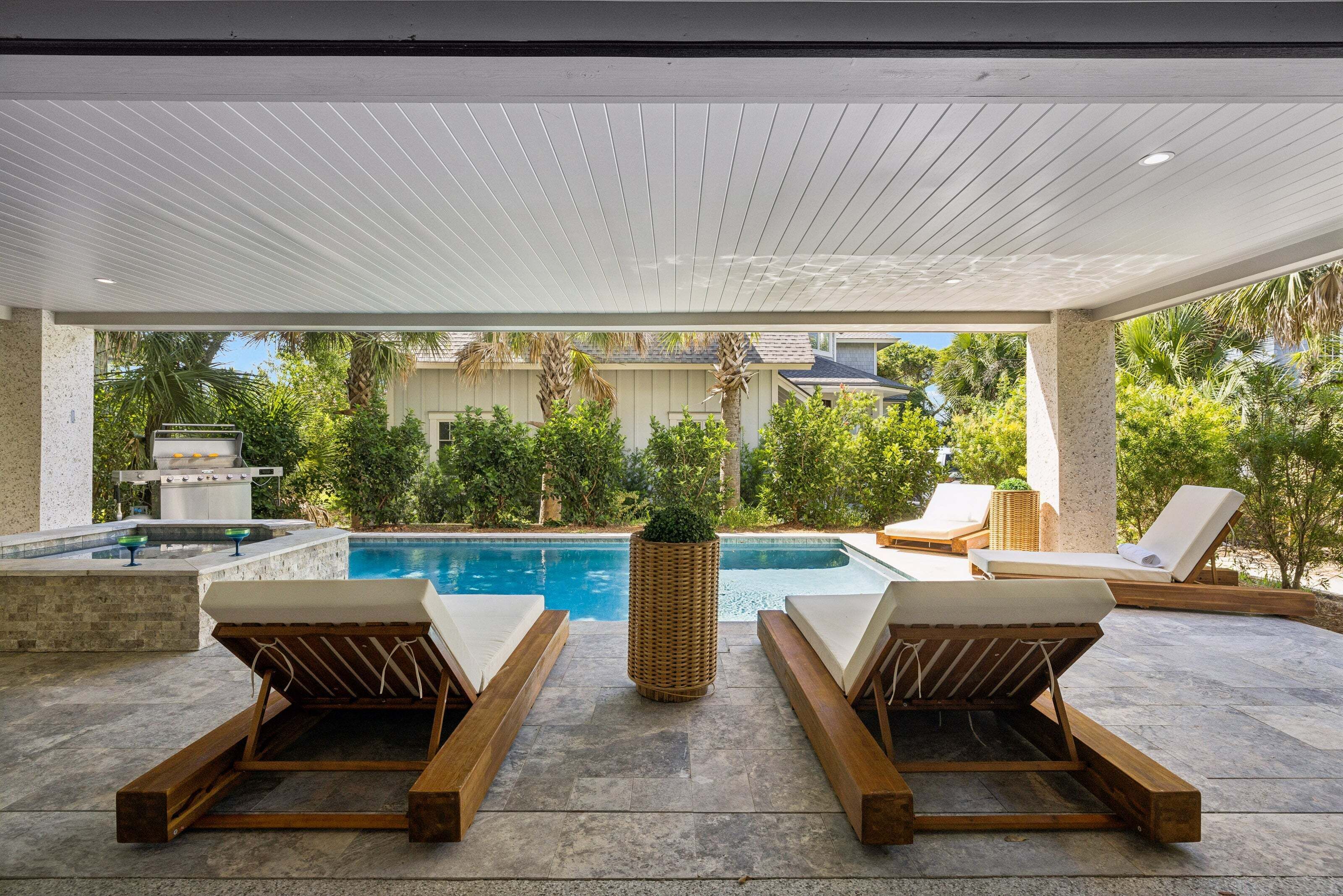 Un espace aménagé au bord de la piscine, avec des chaises longues, une piscine et une pergola.