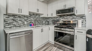 A modern kitchen with light wood cabinets, a stainless steel range, a microwave, and a dishwasher. - Central 3BR Home | Sleeps 8, 4 Beds + 2 Bathrooms (Calgary)
