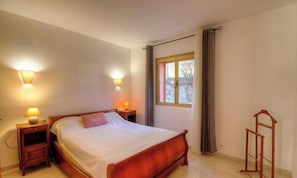 Ein Schlafzimmer mit einem hölzernen Bett, zwei Nachttischlampen, einem Fenster mit Vorhängen und einer Holzleiter.