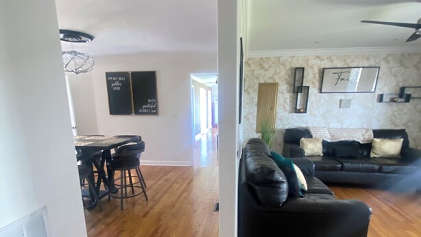 A spacious living area with a black leather sofa, a dining table with chairs, and a kitchen in the background. - Tranquil 3 bedroom 2bath Home with AC in Hendersonville 15mins from Nashville TN (Hendersonville)