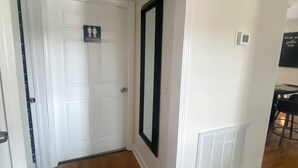 A hallway with a white door, a black-framed mirror, a thermostat, and a sign indicating a restroom. - Tranquil 3 bedroom 2bath Home with AC in Hendersonville 15mins from Nashville TN (Hendersonville)