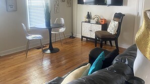 A living room with a black leather sofa, a dining table with chairs, a TV mounted on the wall, and a floor lamp. - Tranquil 3 bedroom 2bath Home with AC in Hendersonville 15mins from Nashville TN (Hendersonville)