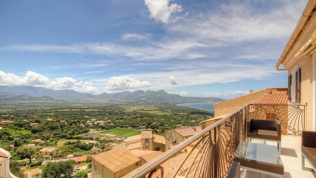 Ein Balkon mit Blick auf eine Küstenlandschaft, darunter Berge und ein Gewässer.