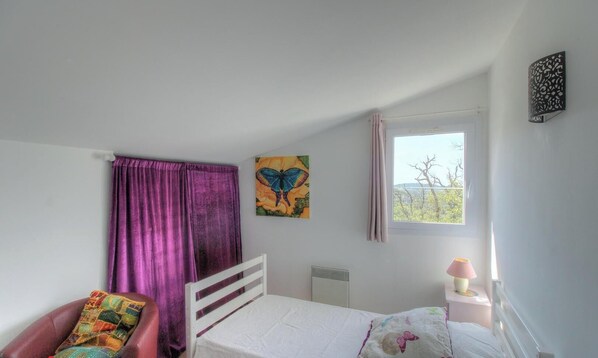 A bedroom with a bed, a chair, a window, a radiator, and a painting. - A Machja - FIGARI - Gîte (FIGARI)