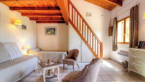 A cozy living room with a wooden staircase, a sofa, a chair, a small table, and a dresser. - ORTIGLIESI - SERRA DI FERRO (SERRA DI FERRO)