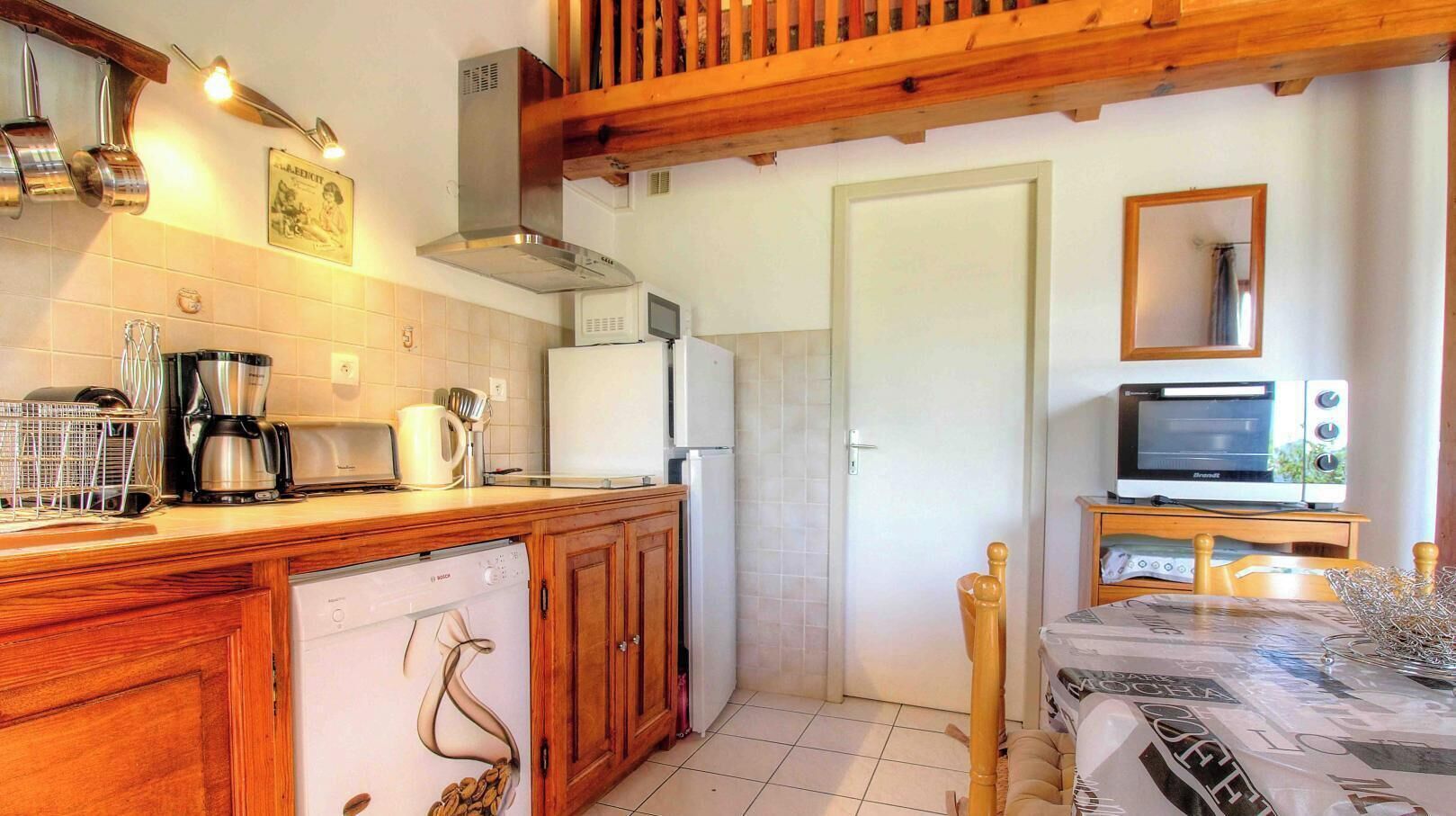 A compact kitchen with wooden cabinets, a Bosch dishwasher, a microwave, and a small oven.
