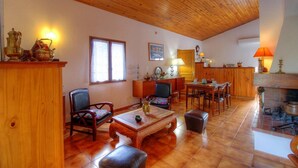 Ein geräumiges Wohnzimmer mit Holzboden, Kamin, Essbereich und einer Küche im Hintergrund.