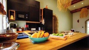 Une cuisine avec un plan de travail en bois, un saladier rempli de fruits, un verre à vin et un four à micro-ondes.