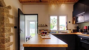 Une cuisine avec un mur en pierre, un plan de travail en bois et des appareils électroménagers modernes.