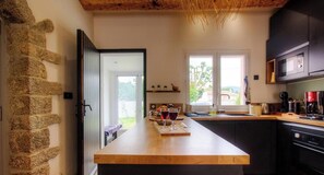 A kitchen with a stone wall, wooden countertop, and modern appliances. - Villa d'Istria - SOLARO (SOLARO)