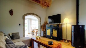Un salon avec un canapé, une table basse, un téléviseur, une lampe et une cheminée.