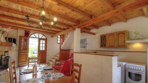 Un interior de madera con una mesa de comedor preparada para cuatro personas, una escalera y una zona de cocina.