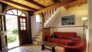 Una habitación con una escalera de madera, un sofá rojo, una mesa de madera y un cuadro en la pared.