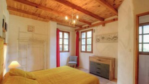 Een slaapkamer met een bed, een bureau, een stoel, een trap en een kroonluchter.