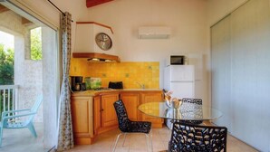 A kitchen with wooden cabinets, a glass table, and a clock on the wall. - Casa Mea - MONTICELLO (MONTICELLO)