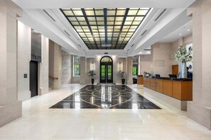 A spacious lobby with a geometric floor pattern, a reception desk, and a large glass ceiling. - Cute with a View & Carparking too (Auckland CBD)