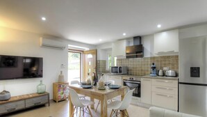 Una cocina moderna con comedor, electrodomésticos integrados y televisor de pantalla plana.