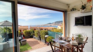 A balcony with a view of the sea, a table with a plant, and a TV mounted on the wall. - AICCU BELLU - AJACCIO (AJACCIO)