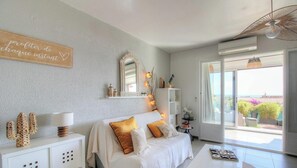 Ein Schlafzimmer mit Bett, Nachttischen, einem Spiegel und Blick ins Freie.
