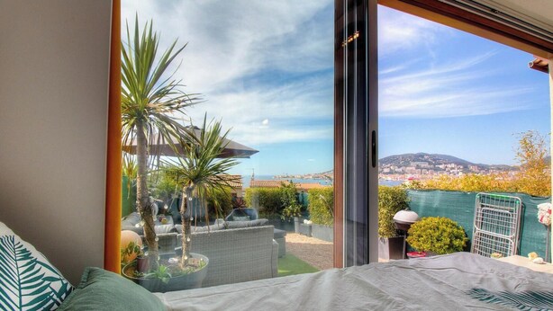 A balcony with a view of a cityscape, a glass door, and outdoor furniture. - AICCU BELLU - AJACCIO (AJACCIO)