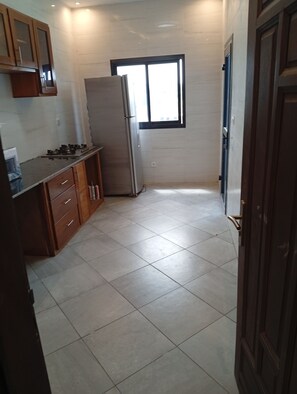 Una cocina compacta con refrigerador, armarios y ventana.